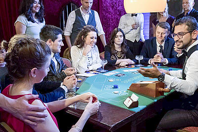 Aufforderung des ersten Spielers beim Baccarat. Croupier fordert den ersten Spielers beim Baccarat auf.