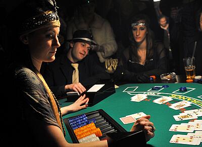 Blackjack-Spieltisch bei einer Casino-Nacht Croupier im 20er Jahre Outfit spielt Blackjack mit den verkleideten Gästen.