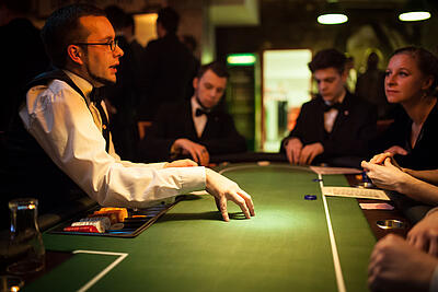 Dealer erklärt Spielregeln beim Pokertisch. Dealer erklärt den Gästen Spielregeln beim Pokern