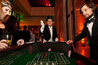 Mann mit Zylinder am Craps-Würfeltisch Mann mit Zylinder wirft die Würfel am Craps-Würfeltisch bei einer 20er Jahre Veranstaltung