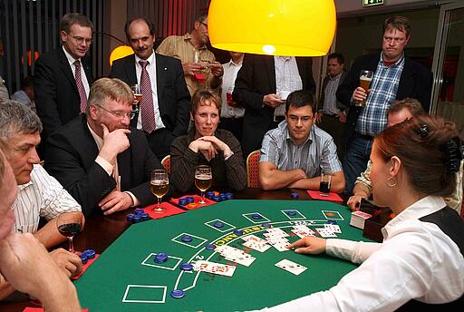 Blackjack-Tisch als Idee für ein Come Together Croupier fragt nach nächster Karte beim Blackjack.