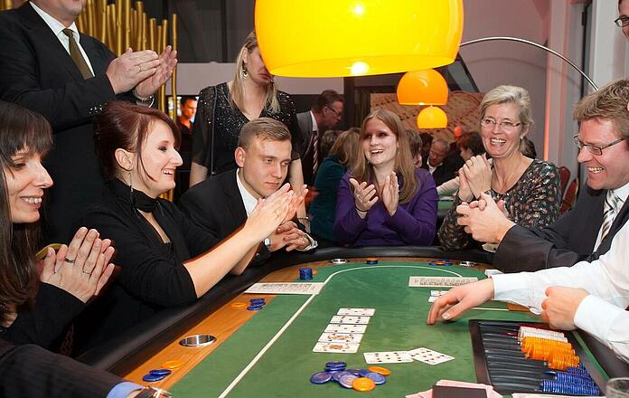 Teilnehmer beim Team Building am Pokertisch applaudieren.
